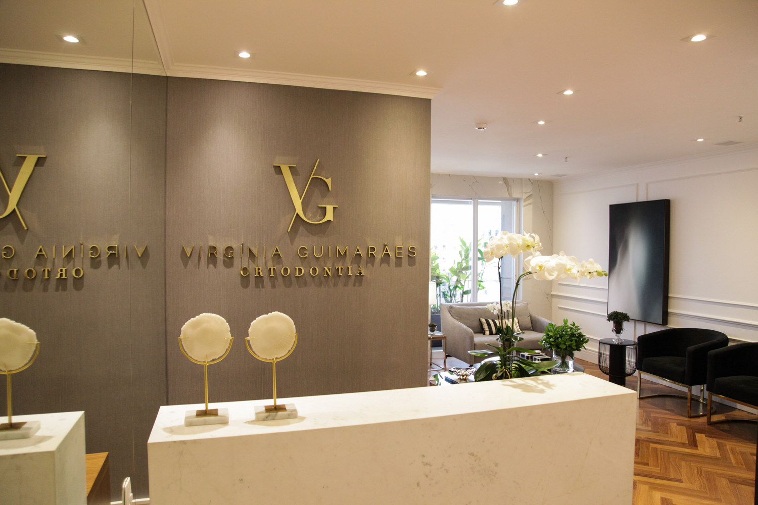 Recepção da clínica Virgínia Guimarães Ortodontia, com a marca VG em dourado